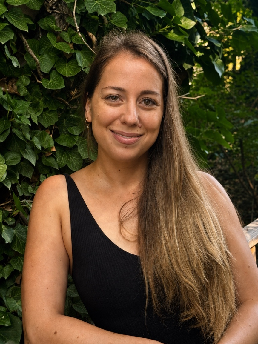Simona seated outdoors in front of ivy